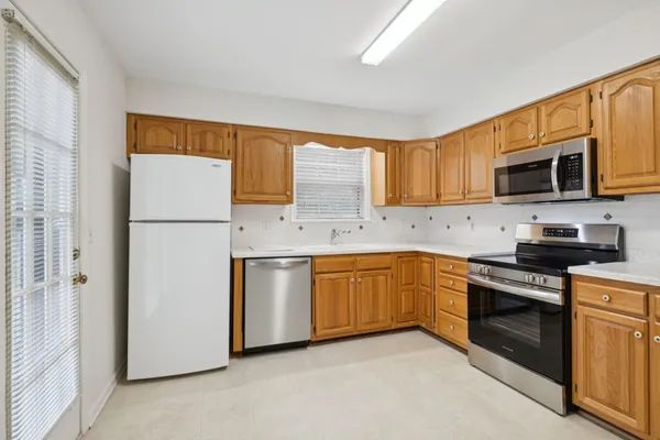 a kitchen with stainless steel appliances granite countertop a stove top oven a sink dishwasher a refrigerator and a microwave oven