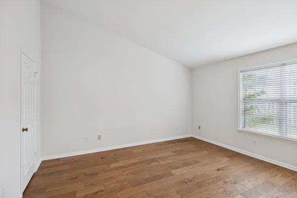 an empty room with wooden floor and window