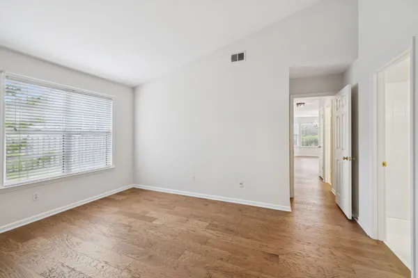 an empty room with wooden floor and windows