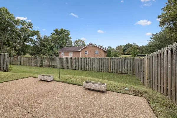 a view of a brick house with a small yard and large trees