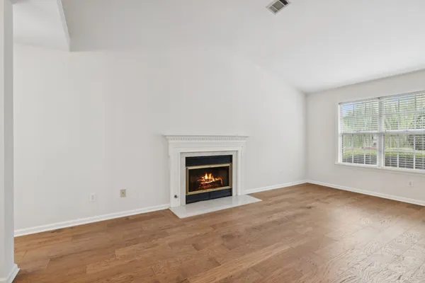 an empty room with wooden floor and a fireplace