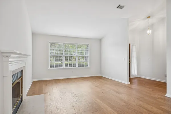 a view of an empty room with wooden floor and a fireplace