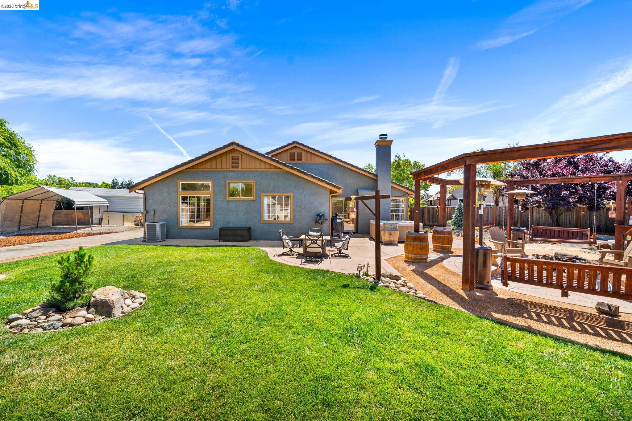1186 El Rio Court Livermore, CA 94551 - Photo 46 of 60 Expansive backyard featuring a large green lawn, concrete patio, and a gravel entertainment area with a wooden pergola structure