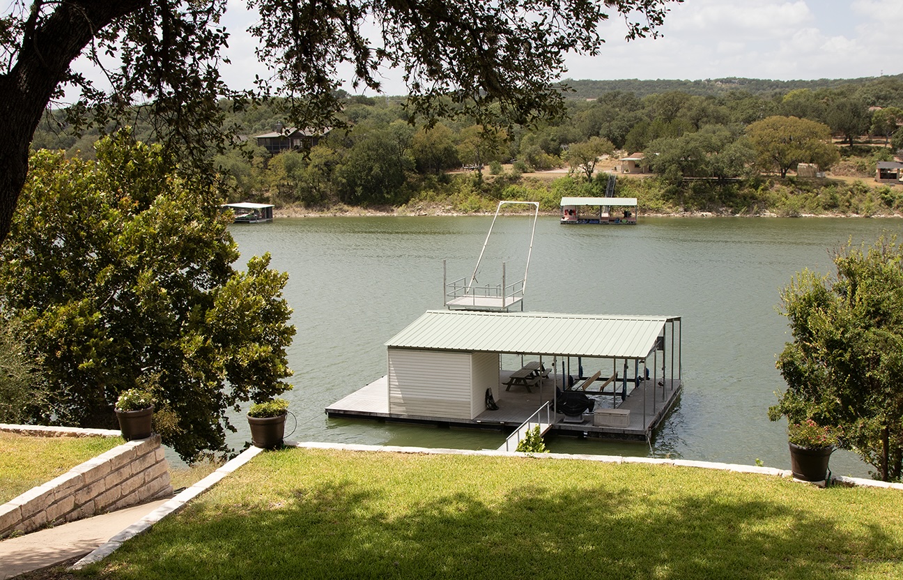 10802 Beach Road Leander, TX 78641 - Photo 31 of 40 A private boat dock extends into the calm water beneath a grassy hillside.