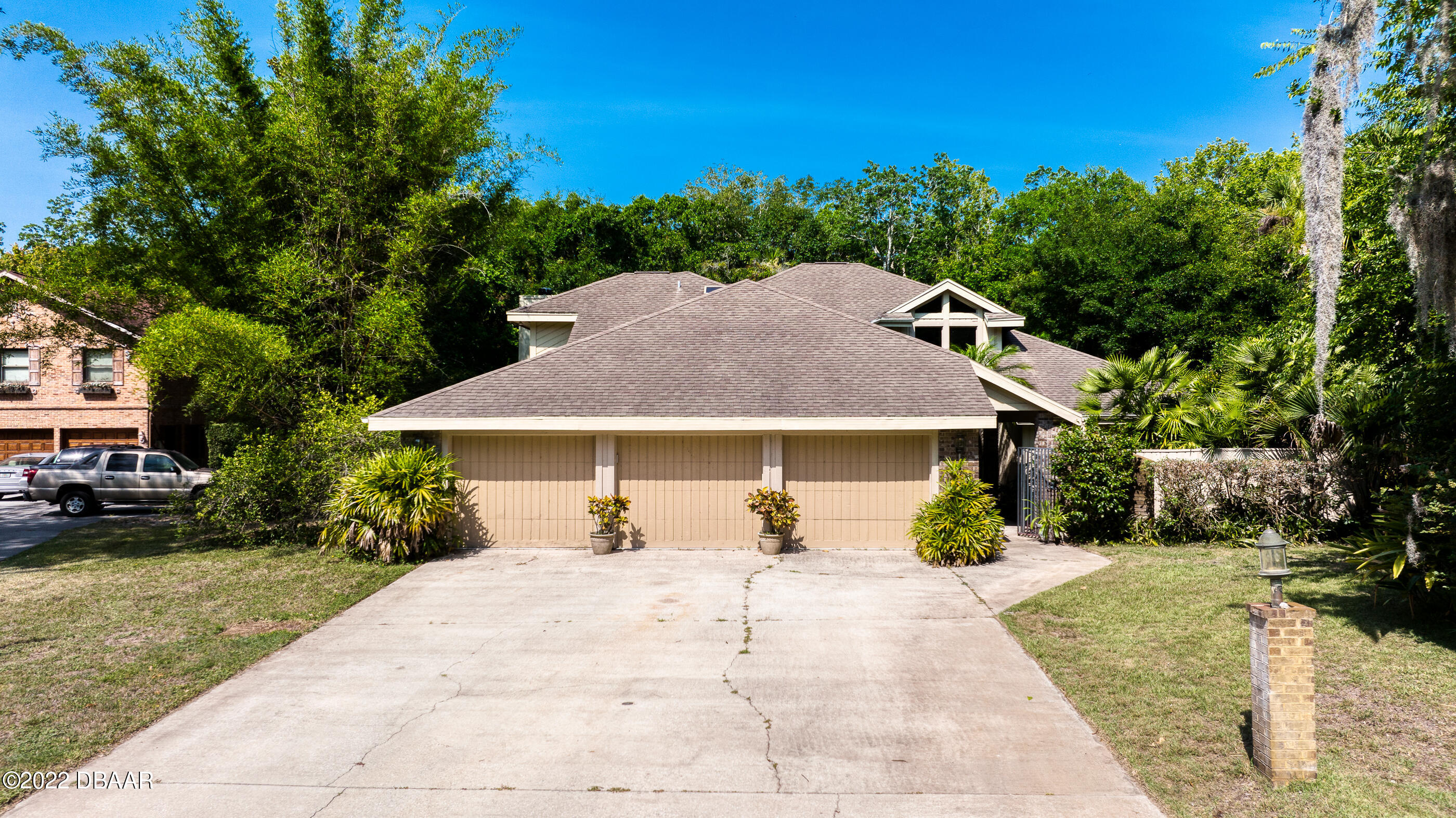 a view of a house with a yard plants and large tree