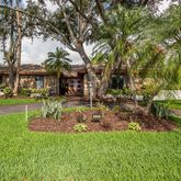 a front view of a house with garden and trees