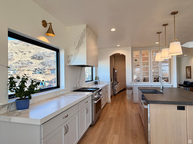 3626 Riverstone Road Mapleton, UT 84664 - Photo 11 of 58 Kitchen featuring arched walkways, premium appliances, dark countertops, decorative light fixtures, and a center island with sink