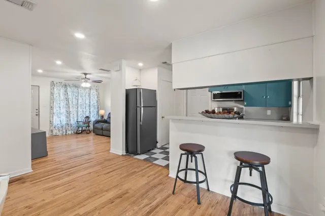 a kitchen with stainless steel appliances a refrigerator and a wooden floor