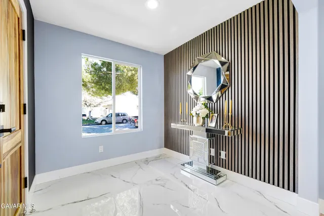 a view of an empty room with window and wooden floor