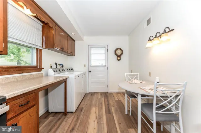 a view of a sink a washer and dryer with wooden cabinets
