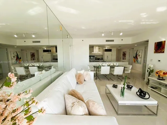 a living room with stainless steel appliances kitchen island granite countertop couches a coffee table and kitchen view