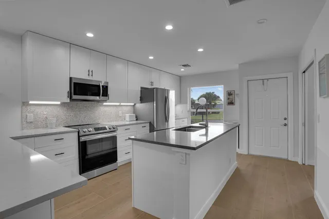 a kitchen with stainless steel appliances granite countertop a stove top oven a sink and a granite counter top
