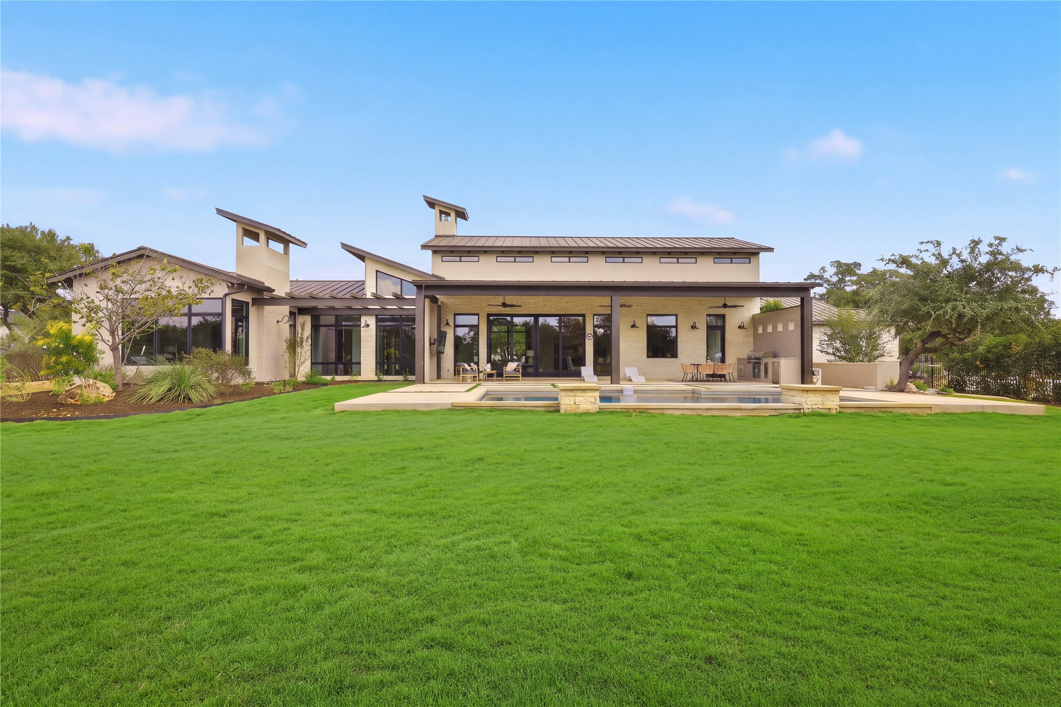 449 Ranch Falls Fair Oaks Ranch, TX 78015 - Photo 33 of 39 An expansive green lawn stretches toward a modern architectural estate featuring a private swimming pool.