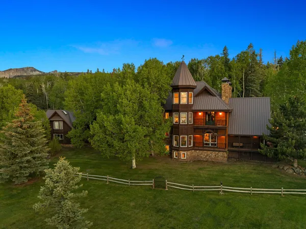 a view of a big house with a big yard and large trees