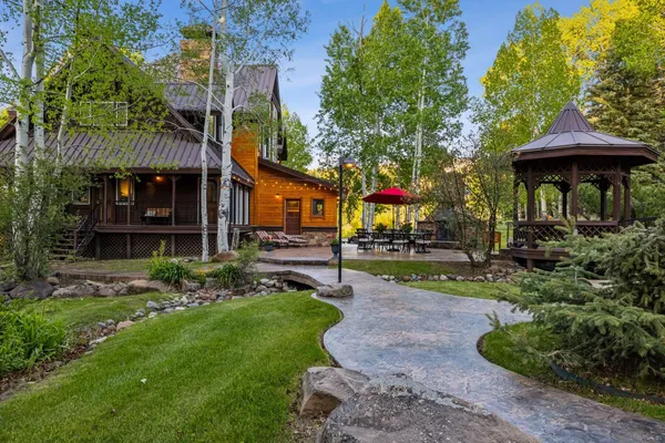 a view of a backyard with plants and a table and chairs under an umbrella