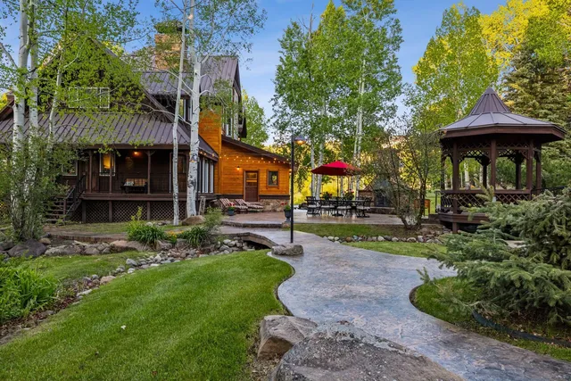 a view of a backyard with plants and a table and chairs under an umbrella