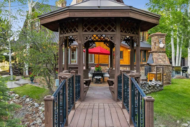 a view of a big house with a big yard and potted plants and large trees