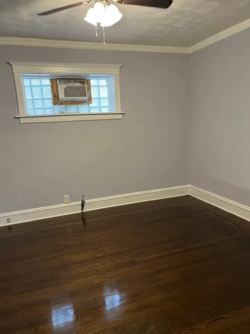a view of an empty room with wooden floor and a chandelier