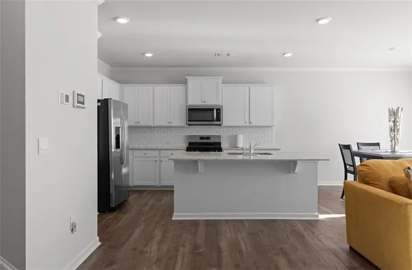 a kitchen with stainless steel appliances granite countertop a refrigerator a stove top oven a sink and dishwasher with wooden floor