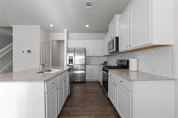 a kitchen with stainless steel appliances kitchen island granite countertop a sink and cabinets