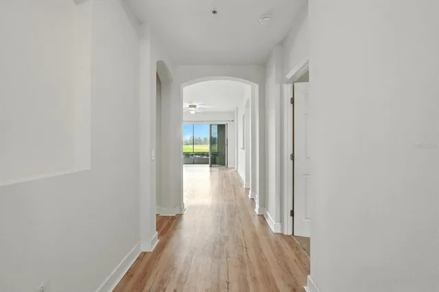 a view of a hallway with wooden floor and a bathroom
