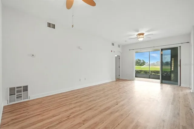 wooden floor in an empty room with a chandelier fan