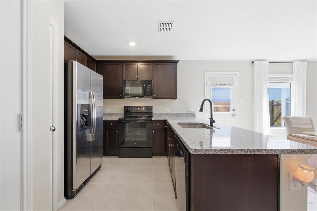 5969 Sumlin Way Princeton, TX 75407 - Photo 9 of 26 a kitchen with granite countertop a refrigerator and a sink