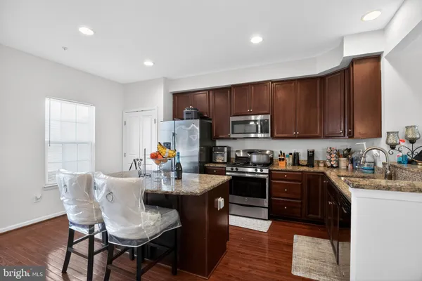 a kitchen with granite countertop a stove top oven a sink dishwasher a dining table and chairs with wooden floor