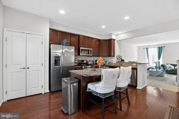 a kitchen with stainless steel appliances kitchen island granite countertop a dining table chairs refrigerator and sink