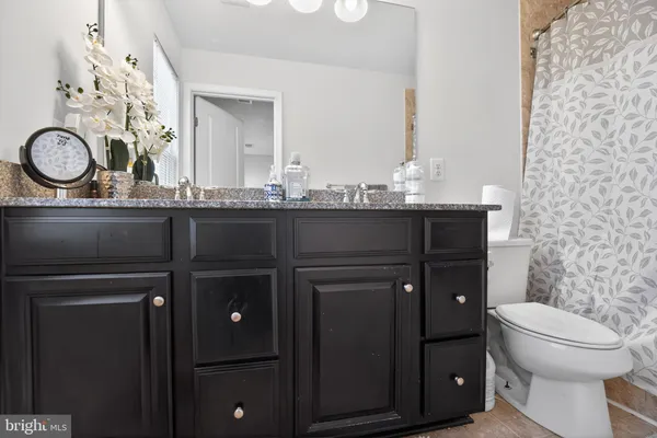 a bathroom with a granite countertop toilet sink and mirror
