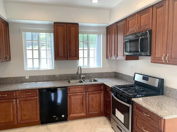 a kitchen with granite countertop stainless steel appliances a sink stove and cabinets