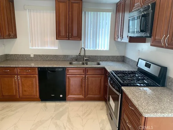 a kitchen with granite countertop a sink a stove and cabinets