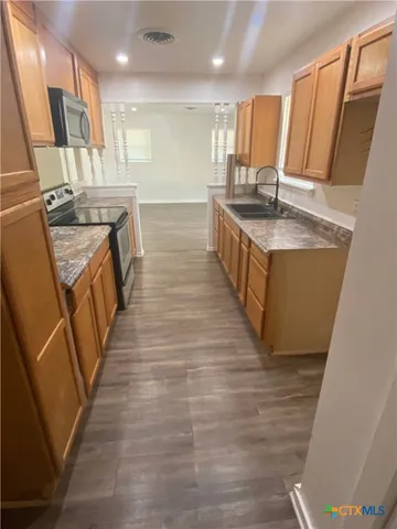 a large kitchen with a sink a counter top space and cabinets