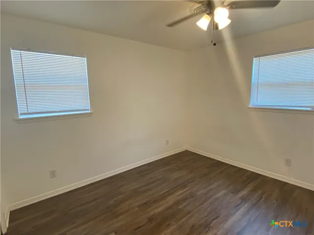 a view of an empty room with wooden floor and a chandelier fan