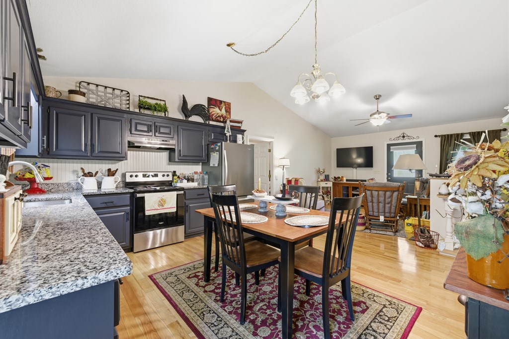 68 West Vineyard Road Hayesville, NC 28904 - Photo 29 of 46 a kitchen with stainless steel appliances granite countertop a stove top oven a sink a dining table and chairs with wooden floor