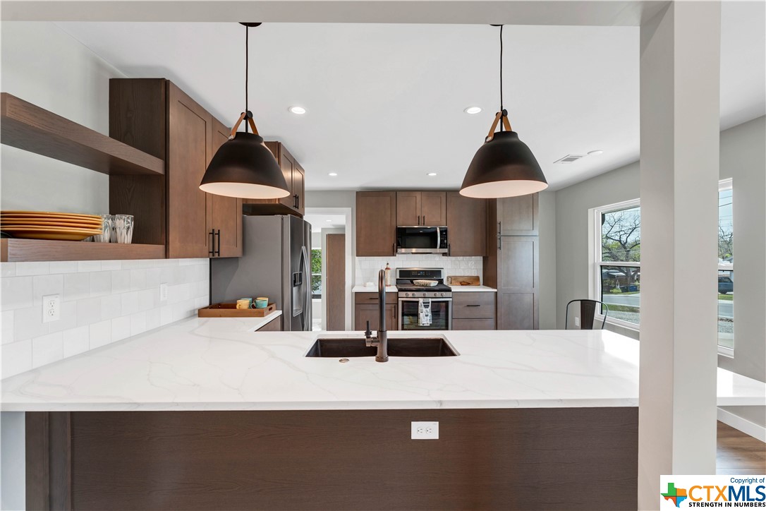 a kitchen with stainless steel appliances a sink a stove a counter top space and cabinets