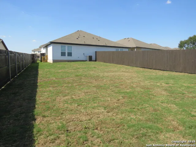 a view of an house with backyard area and wooden fence