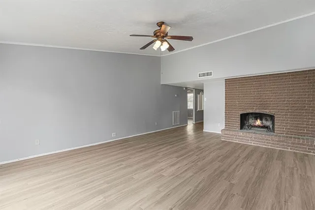 a view of an empty room with wooden floor fireplace and a window
