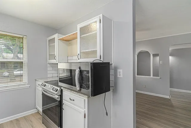 a kitchen with stainless steel appliances granite countertop white cabinets and window