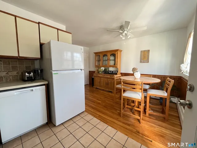 a kitchen with stainless steel appliances a refrigerator a stove a dining table and chairs with wooden floor