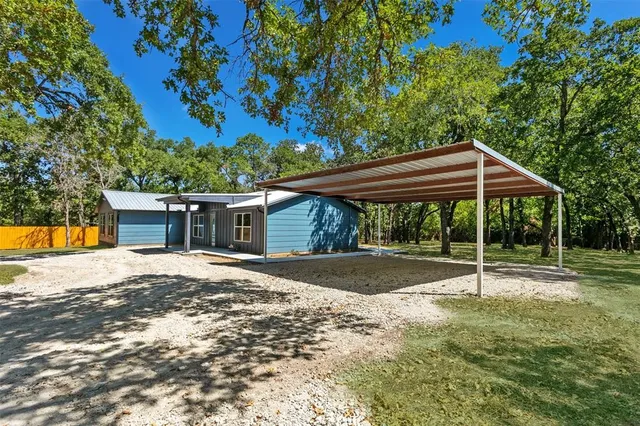 a backyard of a house with table and chairs under an umbrella