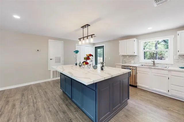 a kitchen with kitchen island granite countertop a sink appliances and cabinets