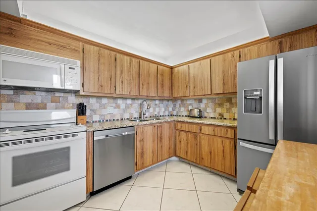 a kitchen with stainless steel appliances granite countertop a refrigerator sink and stove