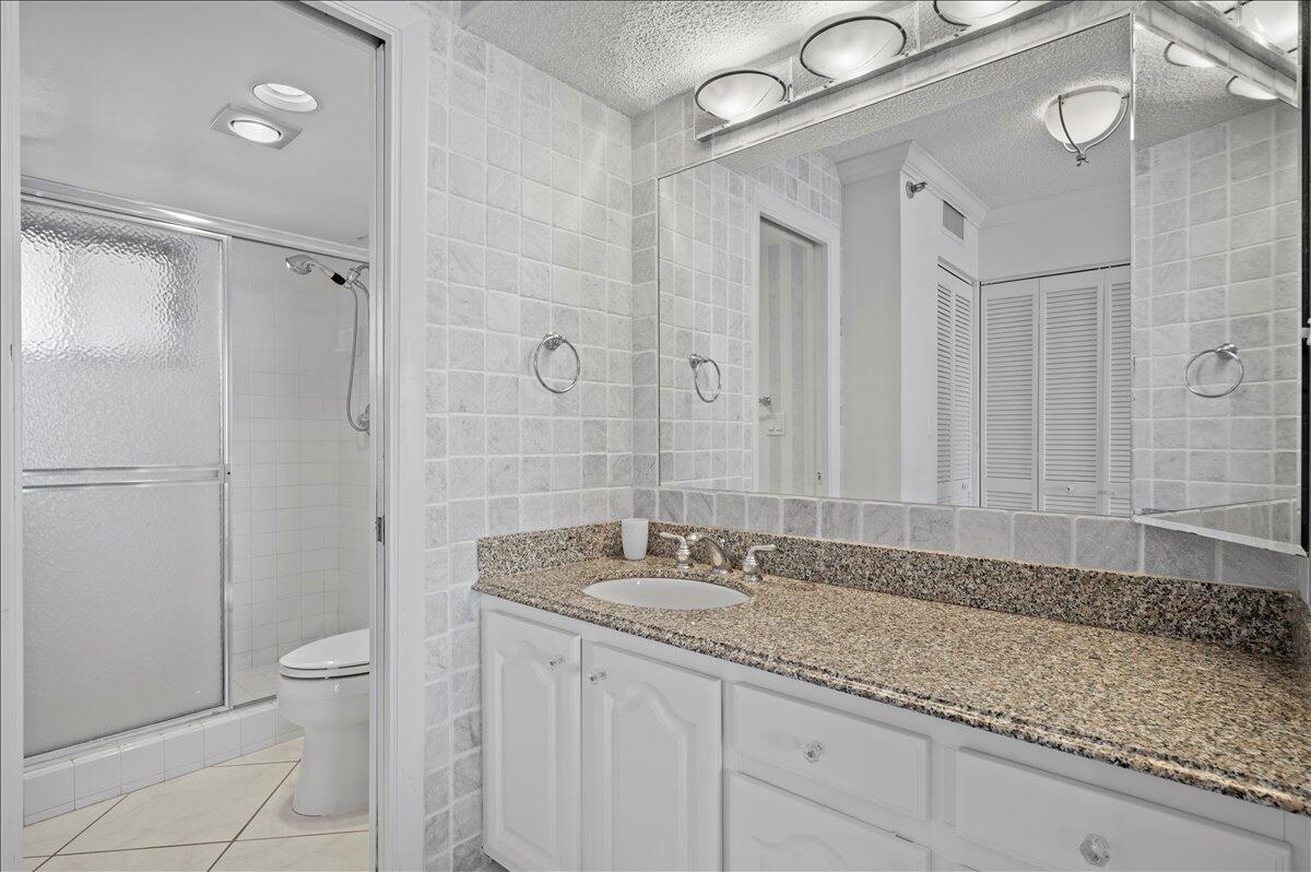 100 Ocean Trail Way, Unit 1403 Jupiter, FL 33477 - Photo 22 of 30 a bathroom with a granite countertop sink a toilet and a shower