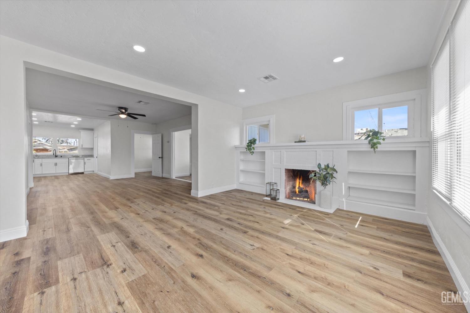 Undisclosed Address Bakersfield, CA 93304 - Photo 15 of 47 a view of a livingroom with a fireplace a chandelier and wooden floor
