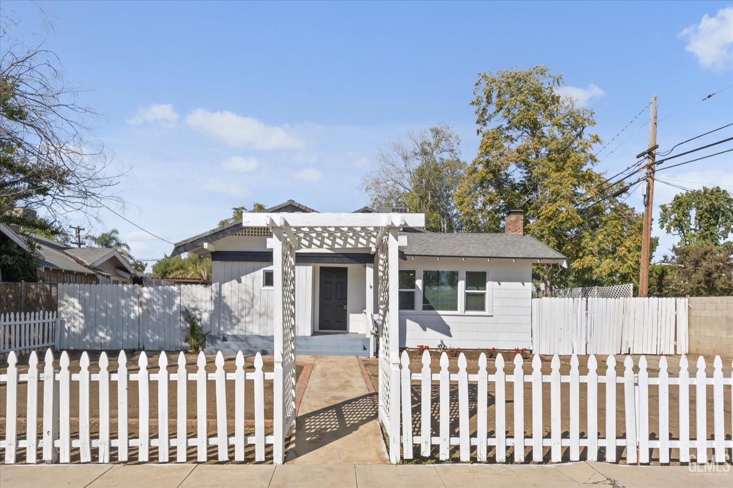 Undisclosed Address Bakersfield, CA 93304 - Photo 4 of 47 a view of a white house with a small yard and a large tree