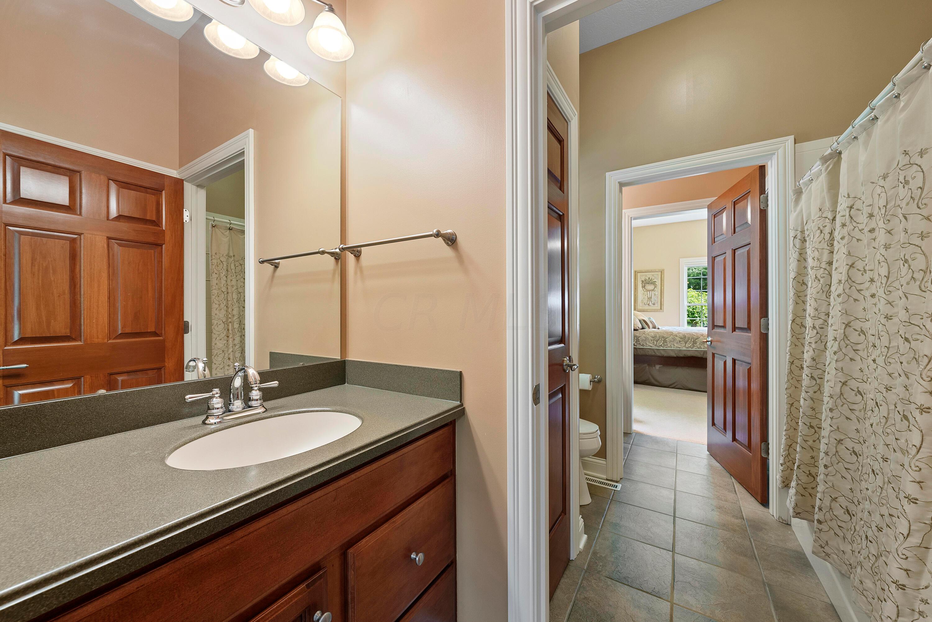 5761 Hughes Road Galena, OH 43021 - Photo 31 of 43 Bedroom Suites 2 & 3 each have their own vanity with sink and doors to the center, shared part of the Bathroom which has ceramic tile flooring, toilet, window, and tub/shower with tile surround.
