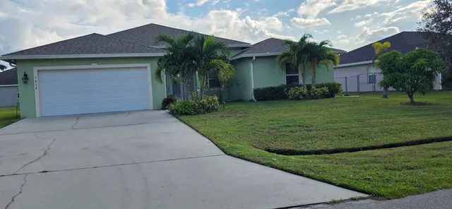 a front view of a house with a yard and potted plants