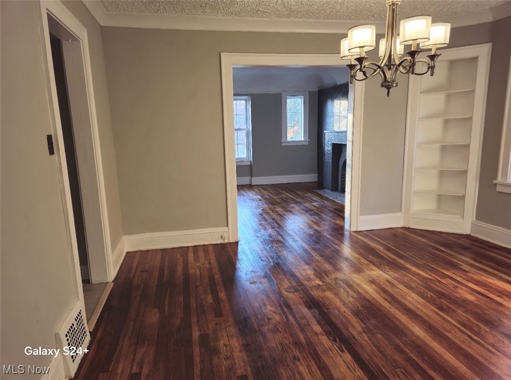 3571 Riedham Road Cleveland, OH 44120 - Photo 10 of 24 Unfurnished dining area featuring built in shelves, dark hardwood / wood-style floors, a textured ceiling, and an inviting chandelier