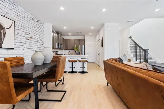 a kitchen with stainless steel appliances kitchen island granite countertop a table chairs in it and wooden floors